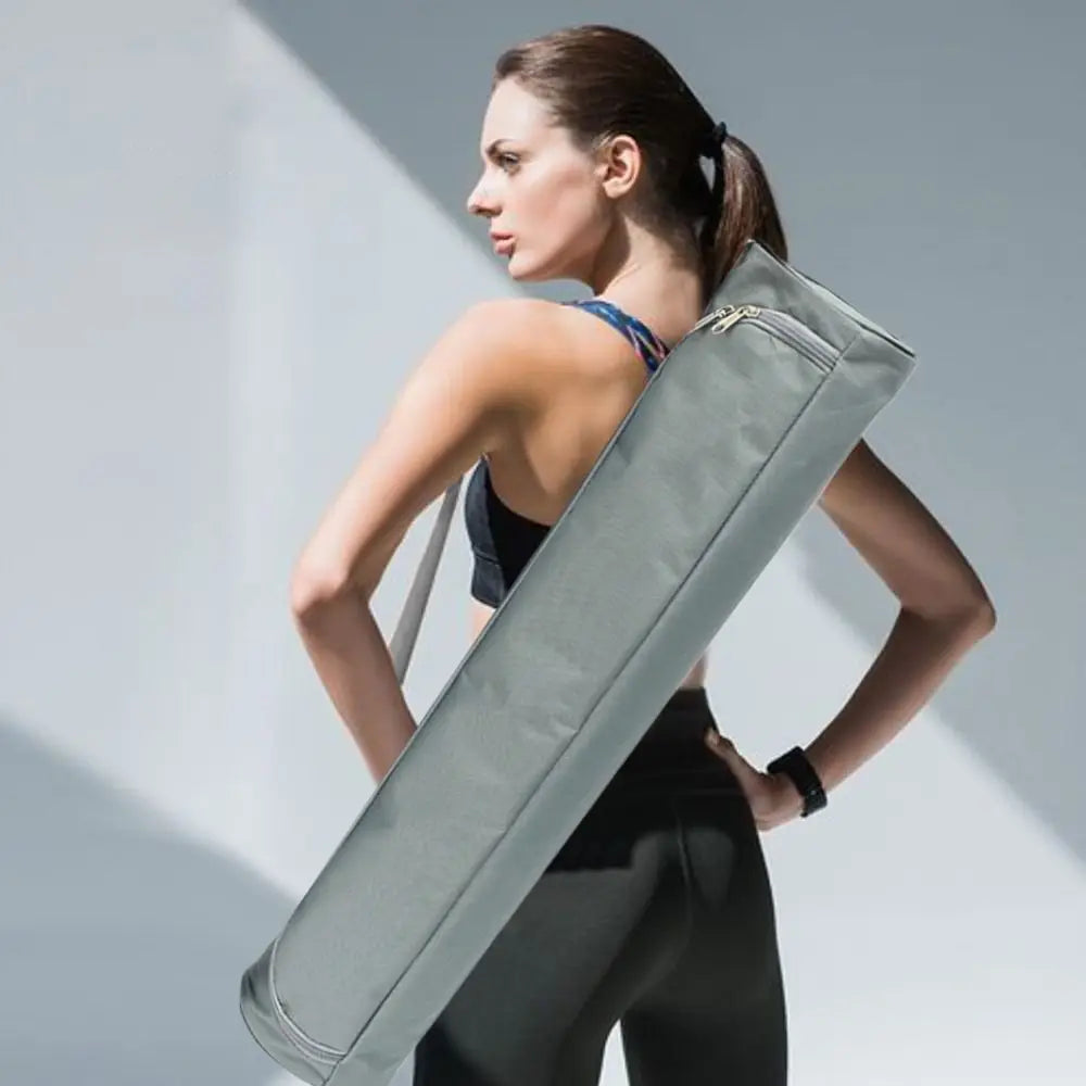 Woman holding a long gray bag against a light background